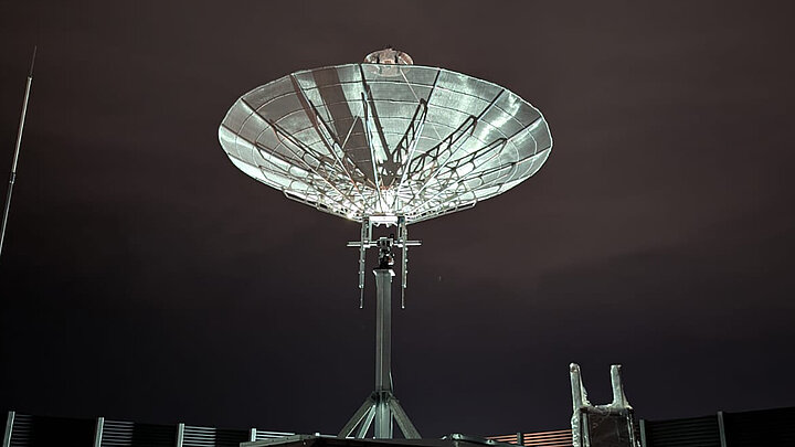 Biała antena do łączności satelitarnej w nocy.