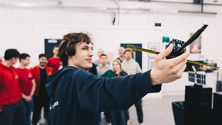 Młody mężczycna trzyma w rękach małego satelitę